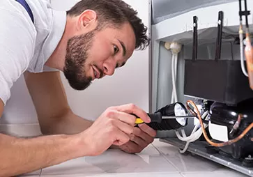 Technician with tools and flashlight fixing wiring in the bottom of a ULT freezer