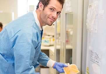 Lab worker smiling while arranging specimins in an ultra low temperature freezer