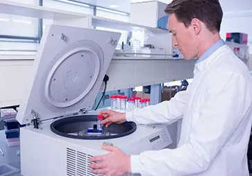 Male lab worker placing specimen in top opening incubator