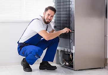 Lab equipment technician with tools fixing wiring in the back of a freezer