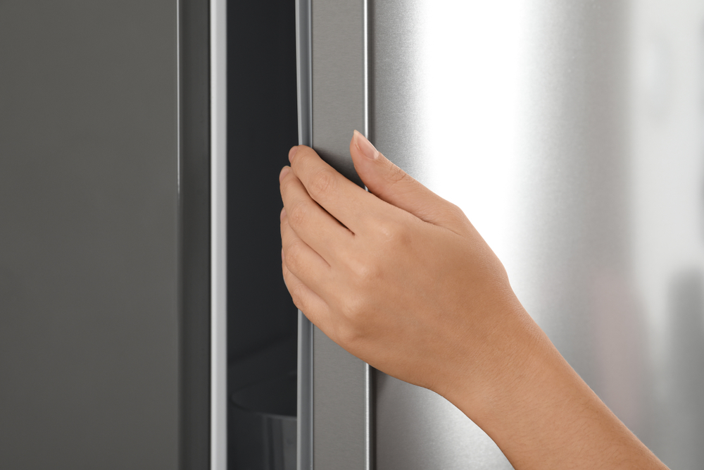Woman opening modern refrigerator door, closeup view