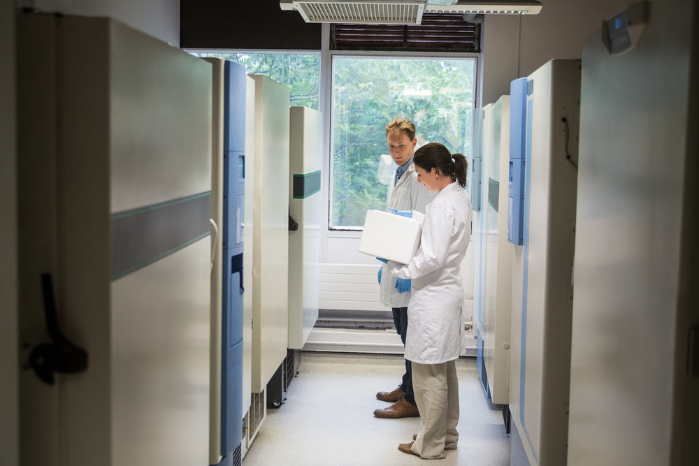 Two scientists beside large fridge unit in the lab