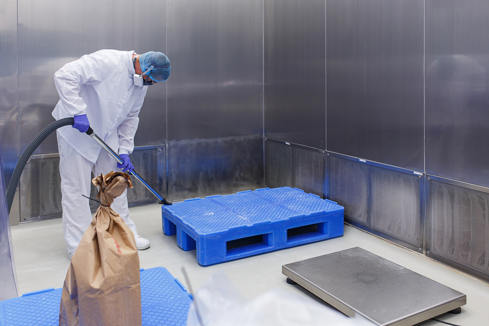 Production room in the medical laboratory. A specialist in protective clothing and a mask makes cleaning of a sterile room.