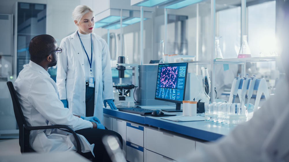 Modern Medical Research Laboratory: Two Scientists Use Computer with Screen Showing DNA Gene Analysis