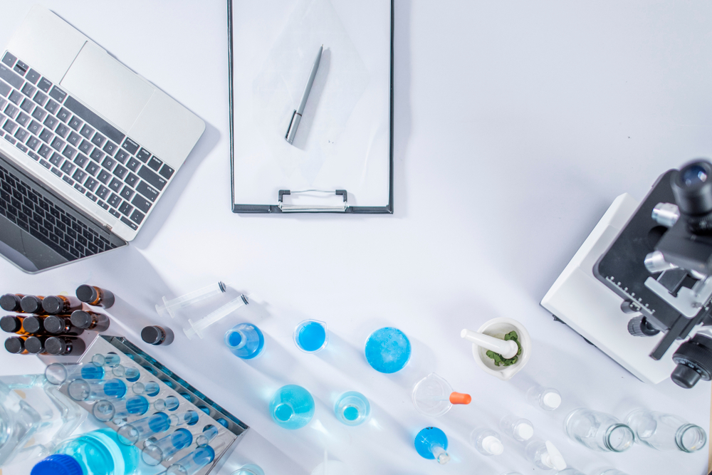 top view workspace in lab with microscope, laptop, and laboratory tools