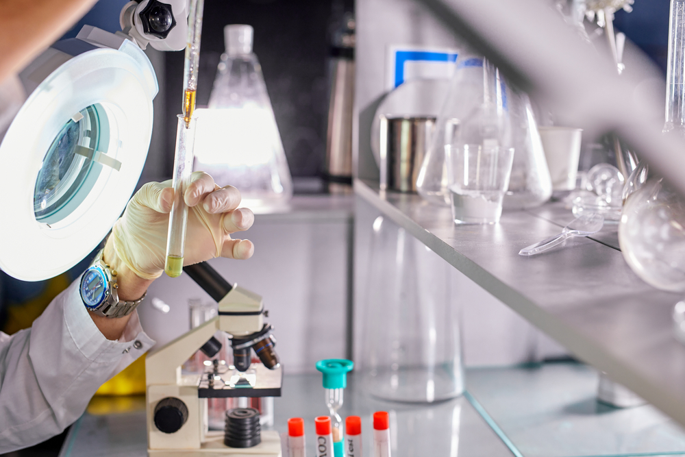 Scientist pours liquid into other tube under the lamp, close-up photo. microbiology concept