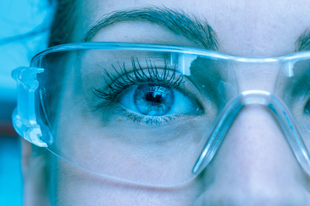Close up of womans eye behind PPE goggles in a lab